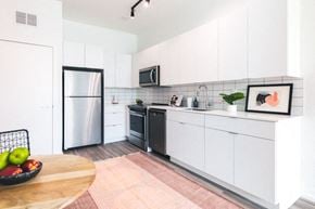 Detroit apartment for rent - a kitchen with white cabinets and a pink rug