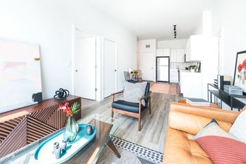 Detroit apartment for rent - A living room with a brown couch and a glass table.