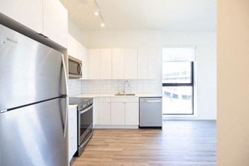 Detroit apartment for rent - A kitchen with a stainless steel refrigerator and white cabinets.