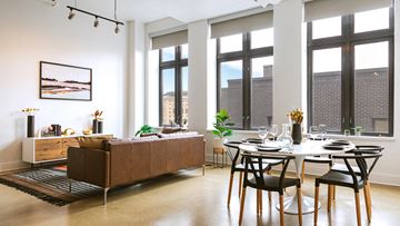 Detroit apartment for rent - a living room with a table and a couch in front of windows
