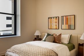 Detroit apartment for rent - A bedroom at The Belle with a bed, two lamps, and two pictures on the wall.