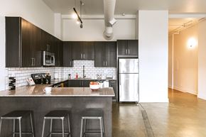 Detroit apartment for rent - a kitchen with black cabinets and stainless steel appliances at The Ferguson Apartments, Detroit, Michigan