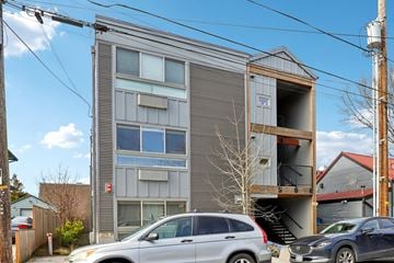Portland apartment for rent - A grey building with a car parked in front.