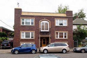 Portland apartment for rent - A blue car is parked in front of a brick building.