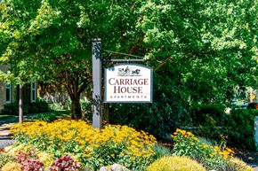 Tigard apartment for rent - A sign for Carriage House Apartments is surrounded by flowers.