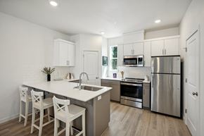 Oregon City townhouse for rent - Modern kitchen with white cabinetry and island seating at Holmes Park Townhomes Apartments, Oregon