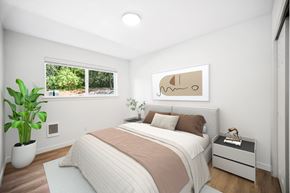 Vancouver apartment for rent - A bedroom with a large bed, a potted plant, and a framed picture on the wall.
