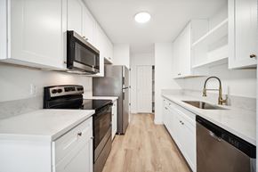 Vancouver apartment for rent - A kitchen with white cabinets and a black microwave.