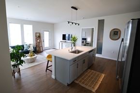 Saukville apartment for rent - A kitchen with a refrigerator, sink, and a dining table with chairs at The Daniels at Northern Gateway Apartments, Wisconsin