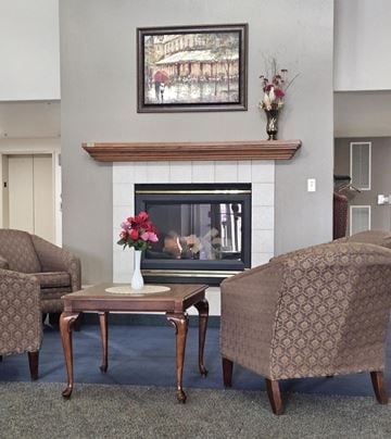 Altoona apartment for rent - A living room with a fireplace, a painting above it, and two chairs.