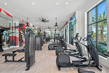 A gym with cardio equipment and large windows
