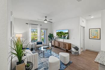 A living room with a couch, a chair, a table, a potted plant, and a painting on the wall.