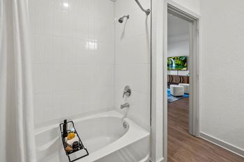 A white bathroom with a white tub and a white shower curtain.