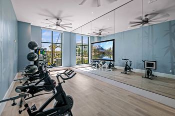A workout room with mirrors and weights on a wooden floor