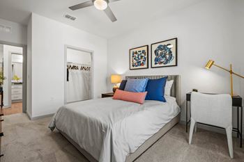 A bedroom with a bed, two lamps, a chair, and two pictures on the wall.