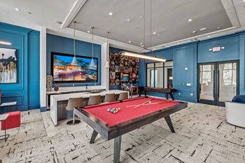 A game room with a red pool table and a television