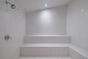 A white bathroom with a shower and white tiles