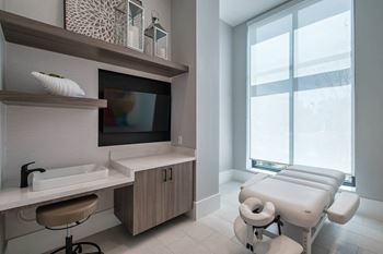 A treatment room at a hospital with a large window and a sink and a chair