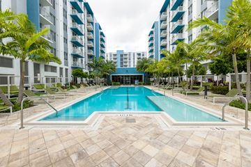 Hialeah apartment for rent - A swimming pool surrounded by palm trees and lounge chairs in front of apartment buildings.