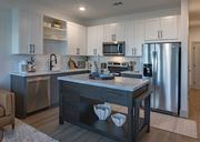 Antioch apartment for rent - Luxury Apartments In Antioch, TN With In-Unit Washer And Dryer - Mainstead At Century Farms - Modern Kitchen With White And Grey Cabinets, A Marble-Topped Island, And Stainless Steel Appliances.