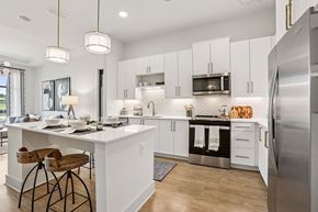 Cumming apartment for rent - A modern kitchen with white cabinets and a wooden bar stool.
