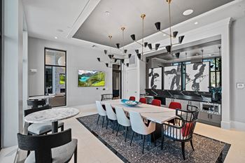 A dining room with a long table and chairs and a kitchen