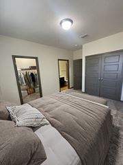 Greenville apartment for rent - Two-Bedroom Apartments in Greenville, SC - Velo Verdae - Cozy Bedroom with Plush Bed, Large Closet Entry, Double Gray Doors, Soft Carpet, and Ensuite Bathroom Doorway.