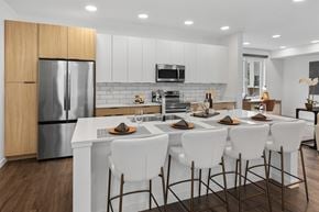 Bozeman townhouse for rent - A modern kitchen with white chairs and a wooden cabinet.