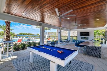 A pool table in a covered patio with a view of a pool