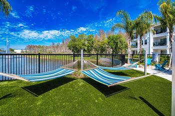A hammock is hanging on a fence next to a body of water