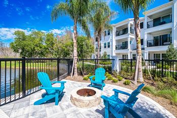 A patio with blue chairs and a fire pit in front of a building