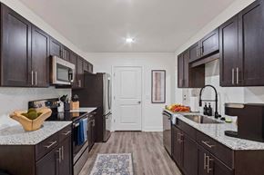 Madison apartment for rent - A kitchen with dark wood cabinets and granite countertops.
