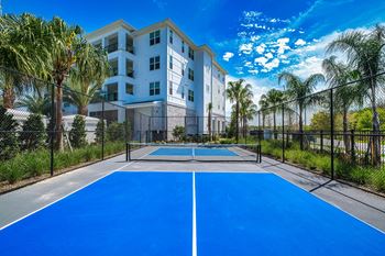 A blue tennis court with apartments in the background