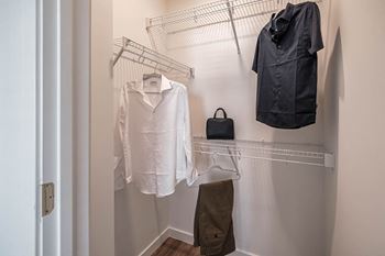 A walk in closet with a shirt and jacket hanging on a rack