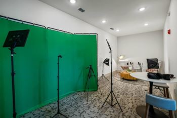 A photo studio with a green screen, lighting equipment, and a table with a bowl of snacks.