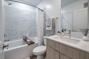 A white toilet sits next to a marble-tiled shower in a modern bathroom
