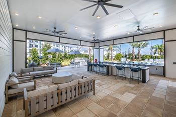 A patio with a table and chairs is surrounded by a wall and has a ceiling fan.