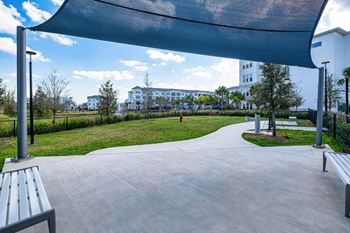 A park with a walkway, benches, and a canopy.