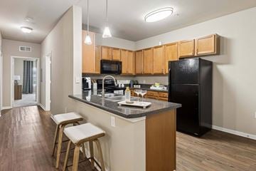 Pensacola apartment for rent - A kitchen with wooden cabinets and a black refrigerator.