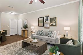 Pensacola apartment for rent - A living room with a grey couch, a coffee table, and a ceiling fan.