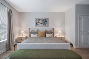 Mcdonough apartment for rent - A bedroom with a large bed and a green blanket.