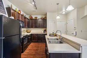 Woodland Park apartment for rent - A kitchen with a black refrigerator and wooden cabinets.