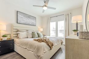 Charlotte apartment for rent - A bedroom with a large bed, a ceiling fan, and a nightstand with a lamp.