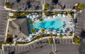 Sarasota apartment for rent - An aerial view of a swimming pool surrounded by palm trees and a parking lot.