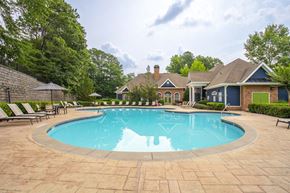 Loganville apartment for rent - A large swimming pool surrounded by a brick patio and lounge chairs.