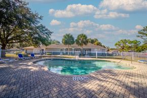 Avon Park apartment for rent - A pool surrounded by a brick patio with a white fence and trees in the background.