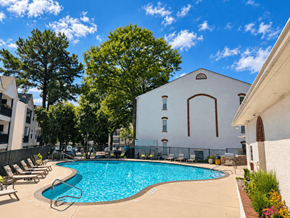 Atlanta apartment for rent - A pool surrounded by trees and a white building.