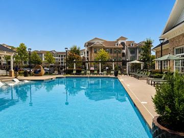 Atlanta apartment for rent - A large swimming pool in front of a building with a clear blue sky.