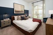 Decatur apartment for rent - 1-Bedroom Apartments in Decatur, GA - Arlo Decatur - Bedroom With Bed, Nightstands with Lamps, Dresser, Armchair, Plush Carpet, Accent Wall,  Framed Wall Art, and Large Window With Blinds and Coverings