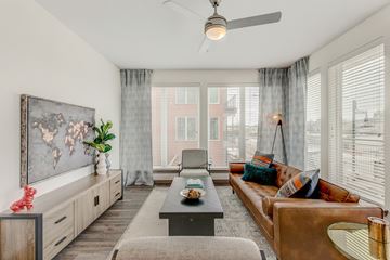 Fort Worth apartment for rent - A living room with a brown couch, a coffee table, and a painting on the wall.